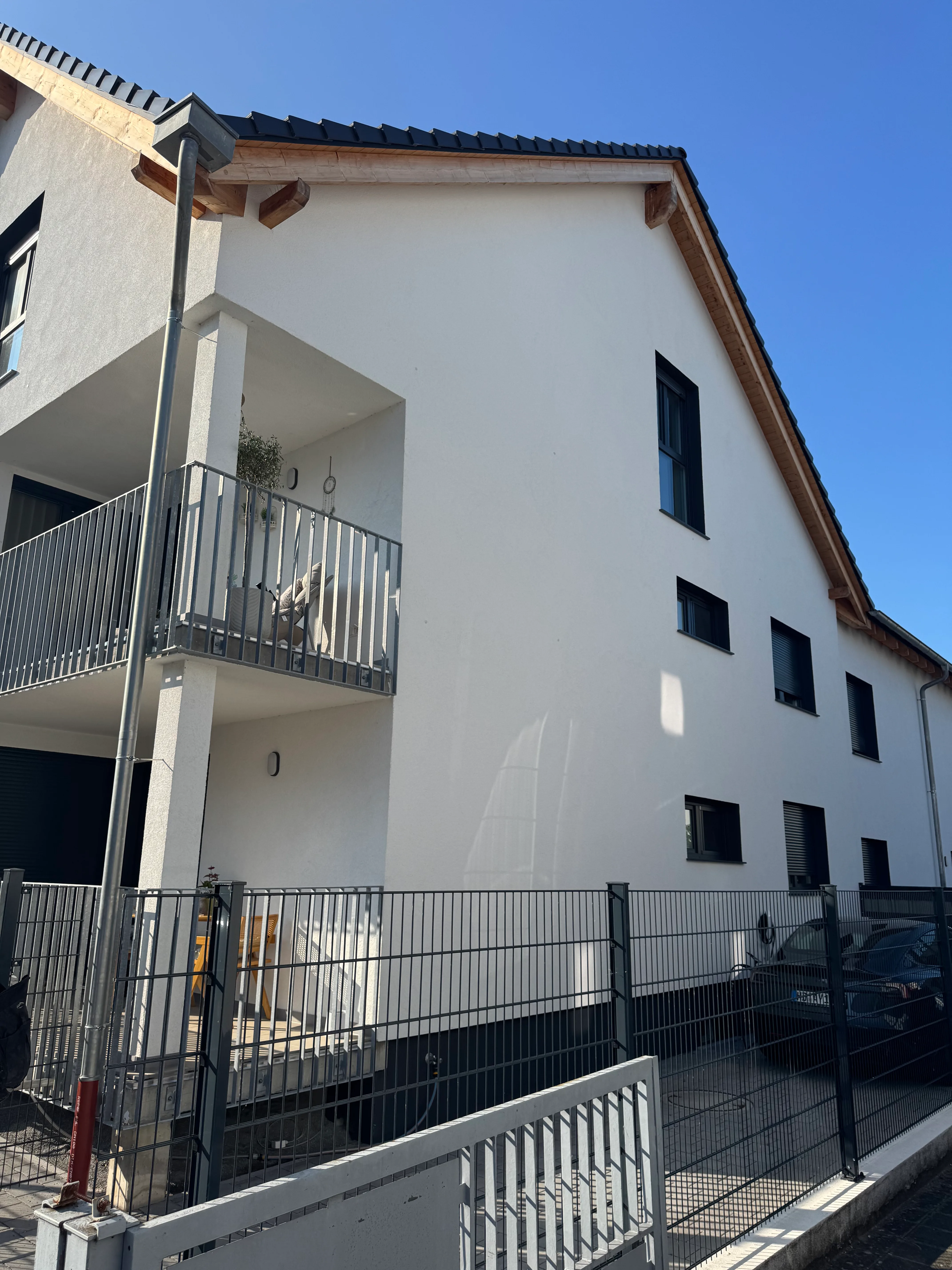 Modernes Wohngebäude mit weißer Fassade und Metallelementen