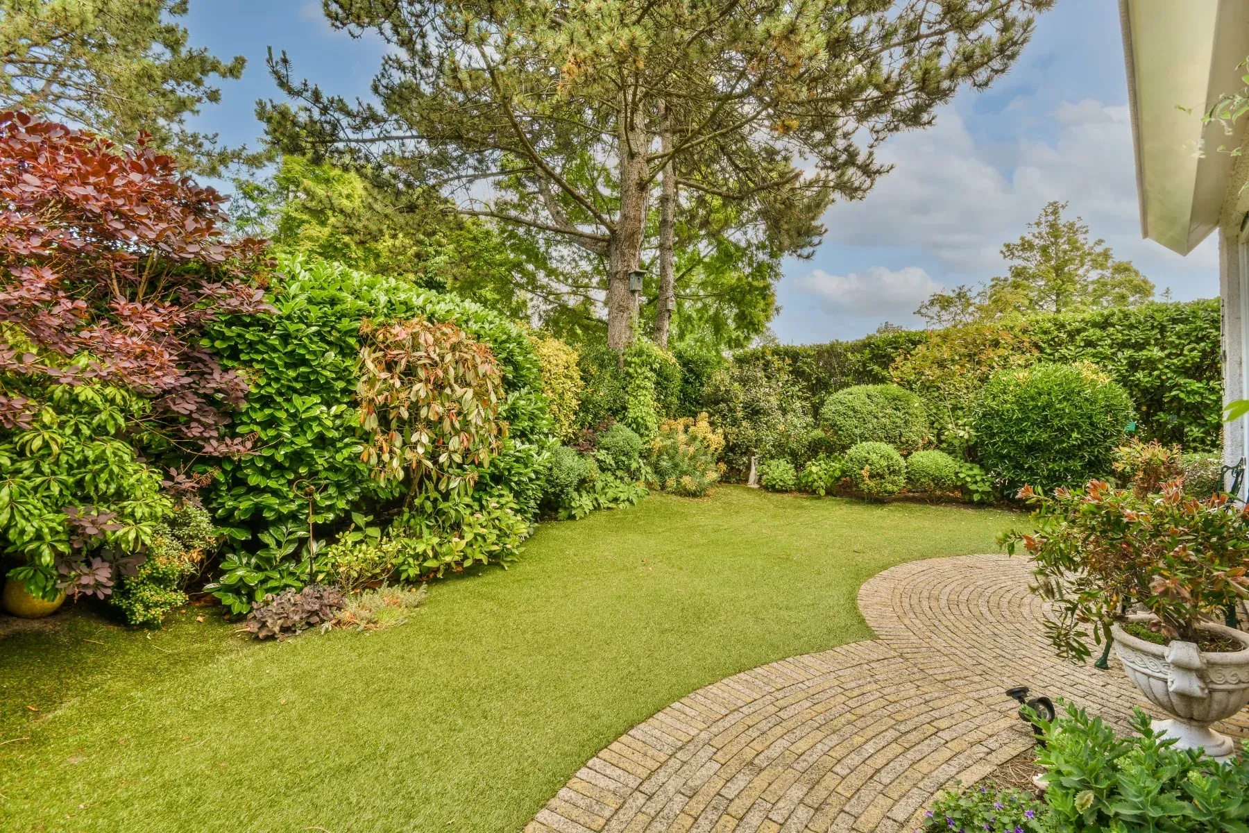Gepflegte Gartenlandschaft mit Rasenfläche und bunten Sträuchern
